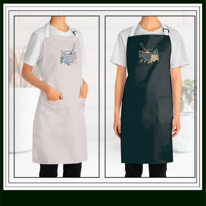 Two aprons, one gray and one green showing embroidery design of a  classic mixing bowl paired with a whisk and delicate floral accents